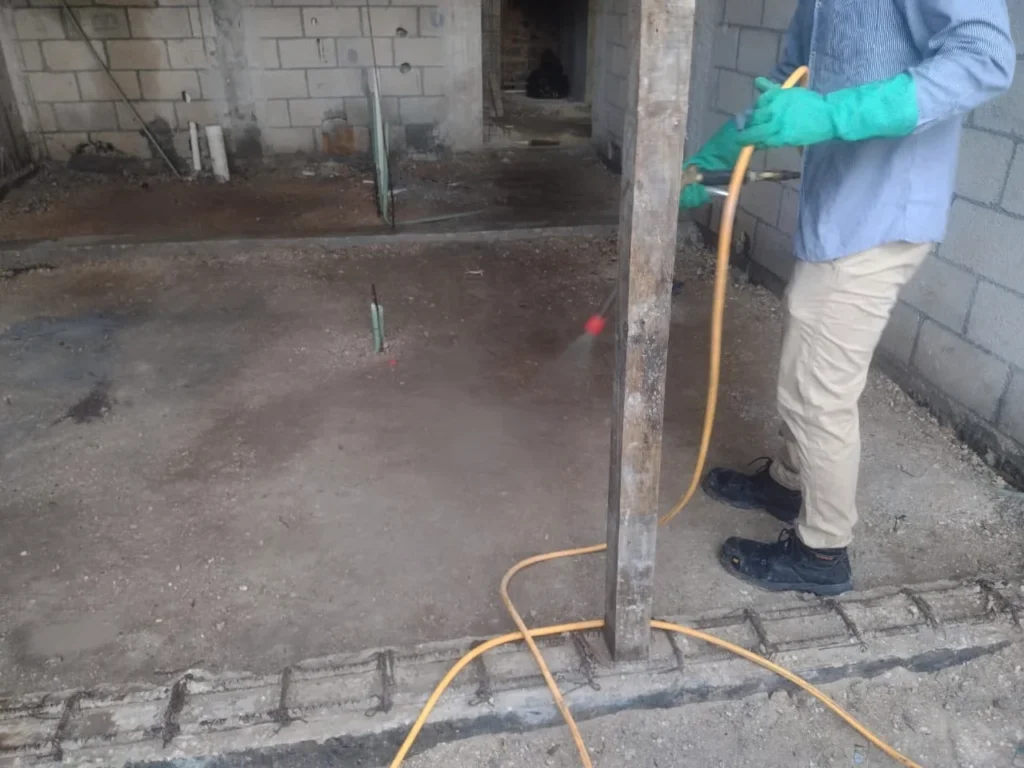 Técnico aplicando tratamiento contra termitas en una estructura en construcción.